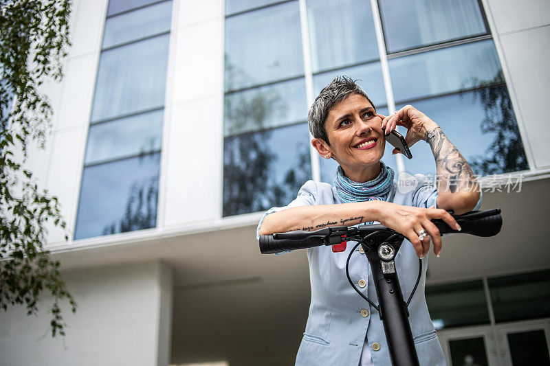 A modern business woman comes to work on an electric scooter, passes by the office building where she works